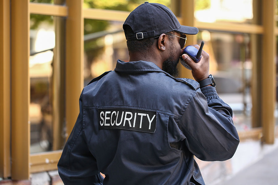 Security Guard Insurance - Security Guard Talking into the Radio While Watching Outside a Building